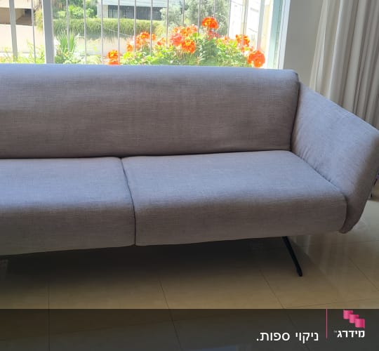 ספה אפורה ליד חלון עם פרחים צבעוניים